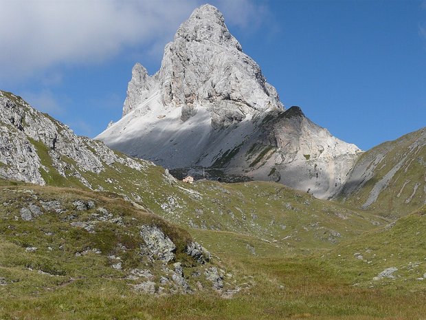 A mountain hut in front of a striking mountain peak